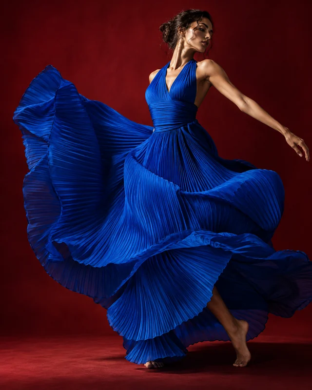 A dancer in a sweeping cobalt dress against a rich oxblood backdrop.